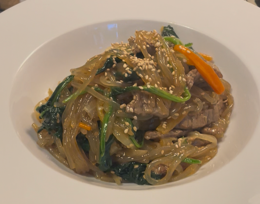 Homemade Japchae, Korean glass noodles stir-fried with beef, spinach, carrots, onions, and sesame seeds